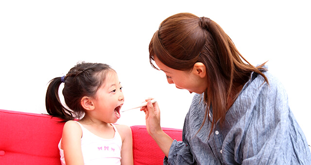 子供の歯を仕上げ磨きするお母さん